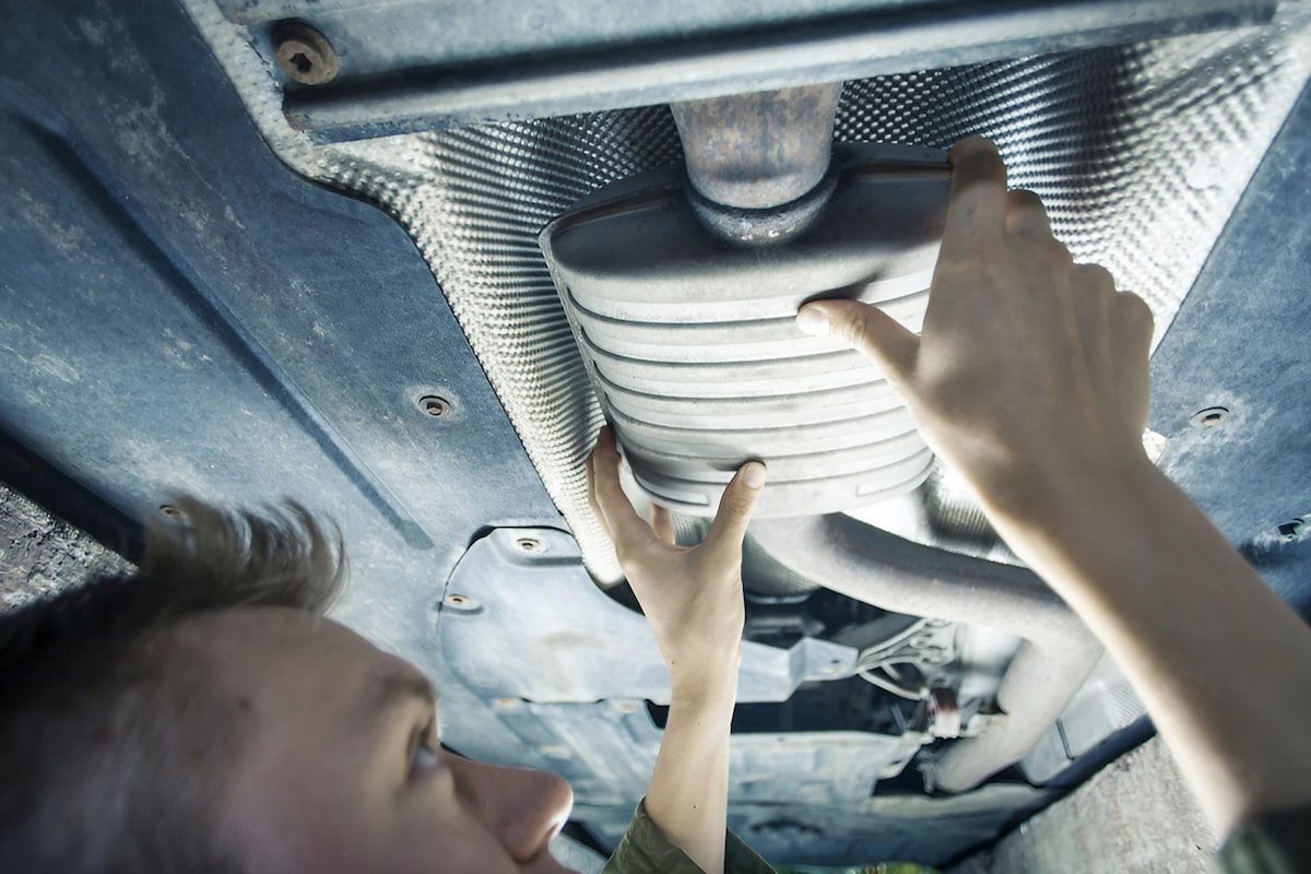 A Skilled Man Is Working on The Underside of A Car — Rum City Exhaust Centre in Bundaberg Central, QLD