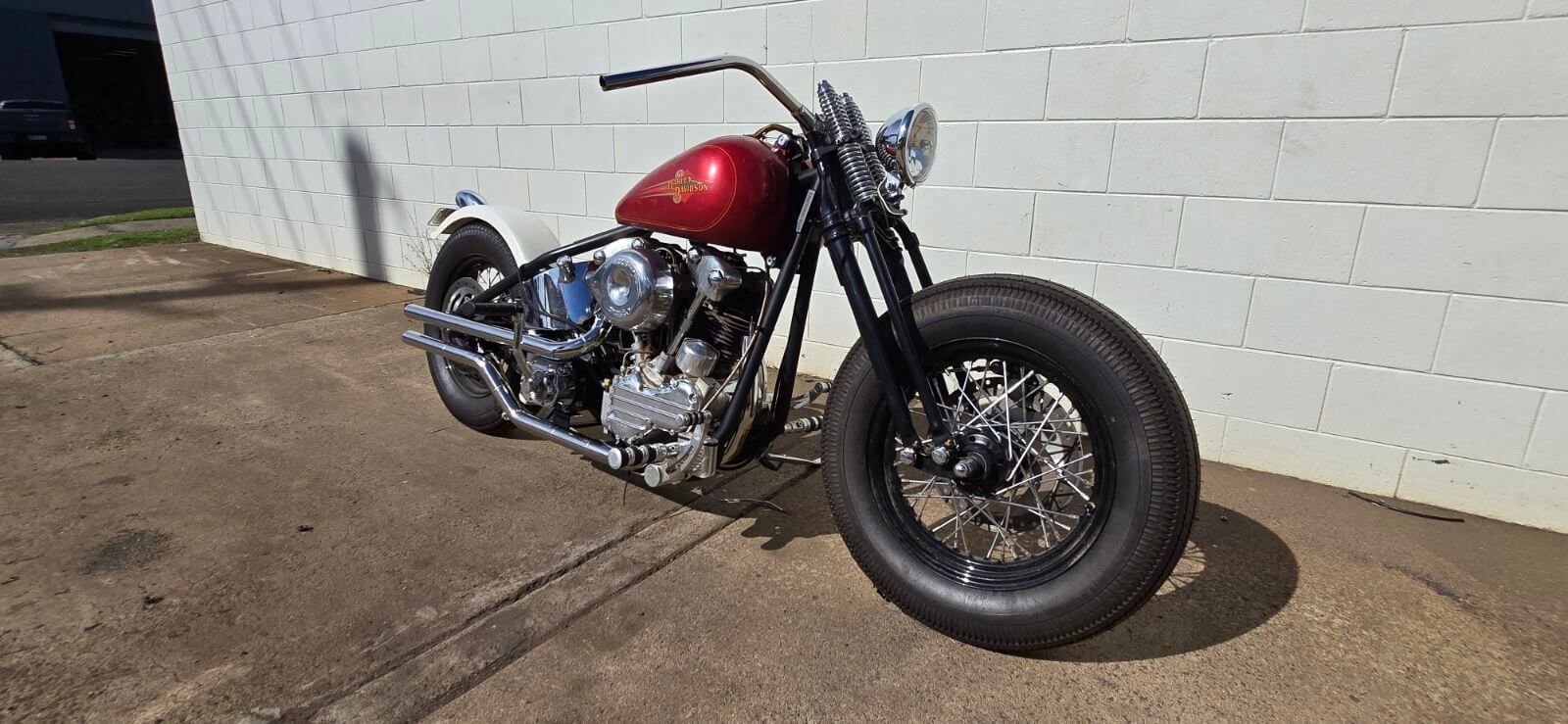 A Red Motorcycle Is Parked in Front of A White Brick Wall — Rum City Exhaust Centre in Bundaberg Central, QLD