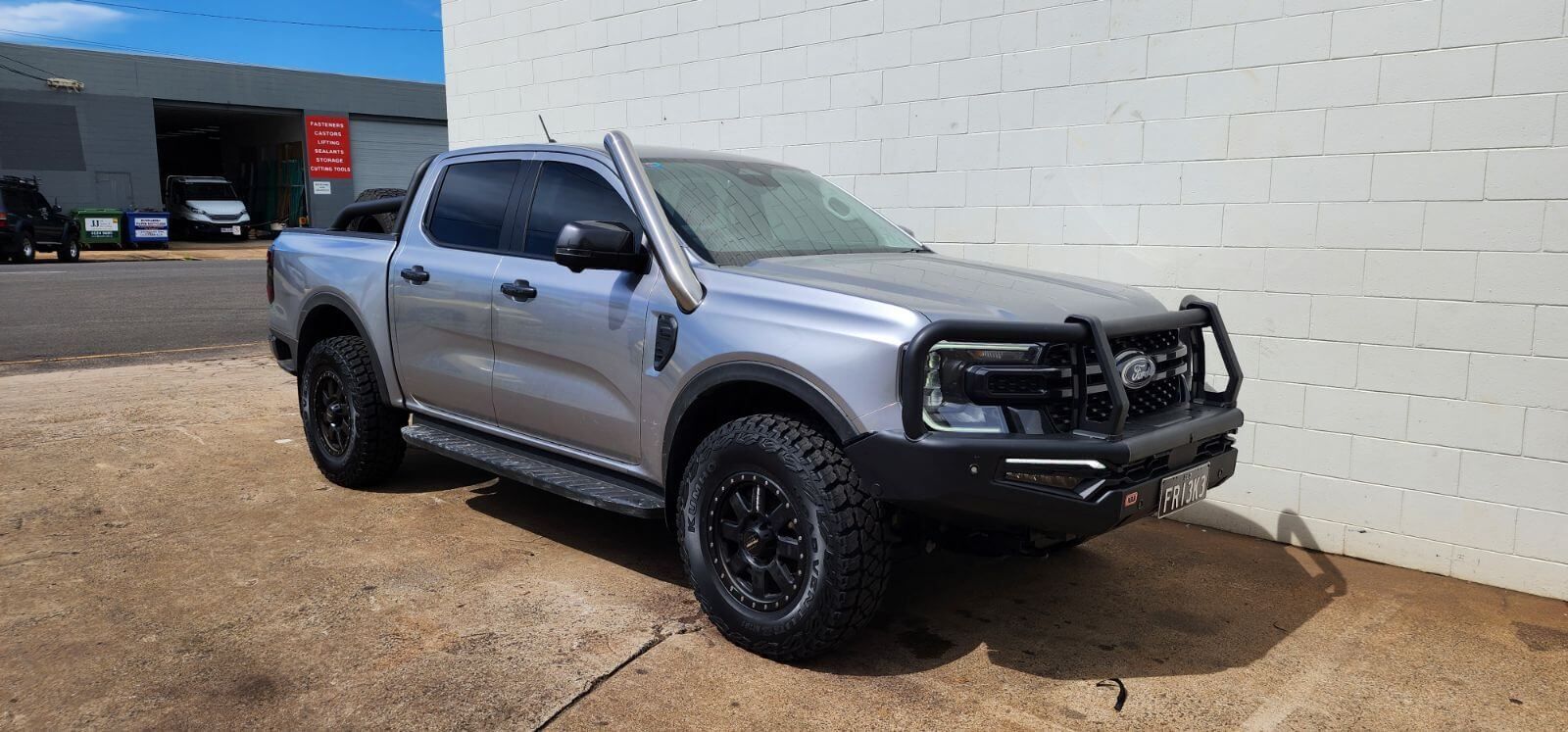 A Silver Pickup Truck Is Parked in Front of A White Brick Building — Rum City Exhaust Centre in Bundaberg Central, QLD