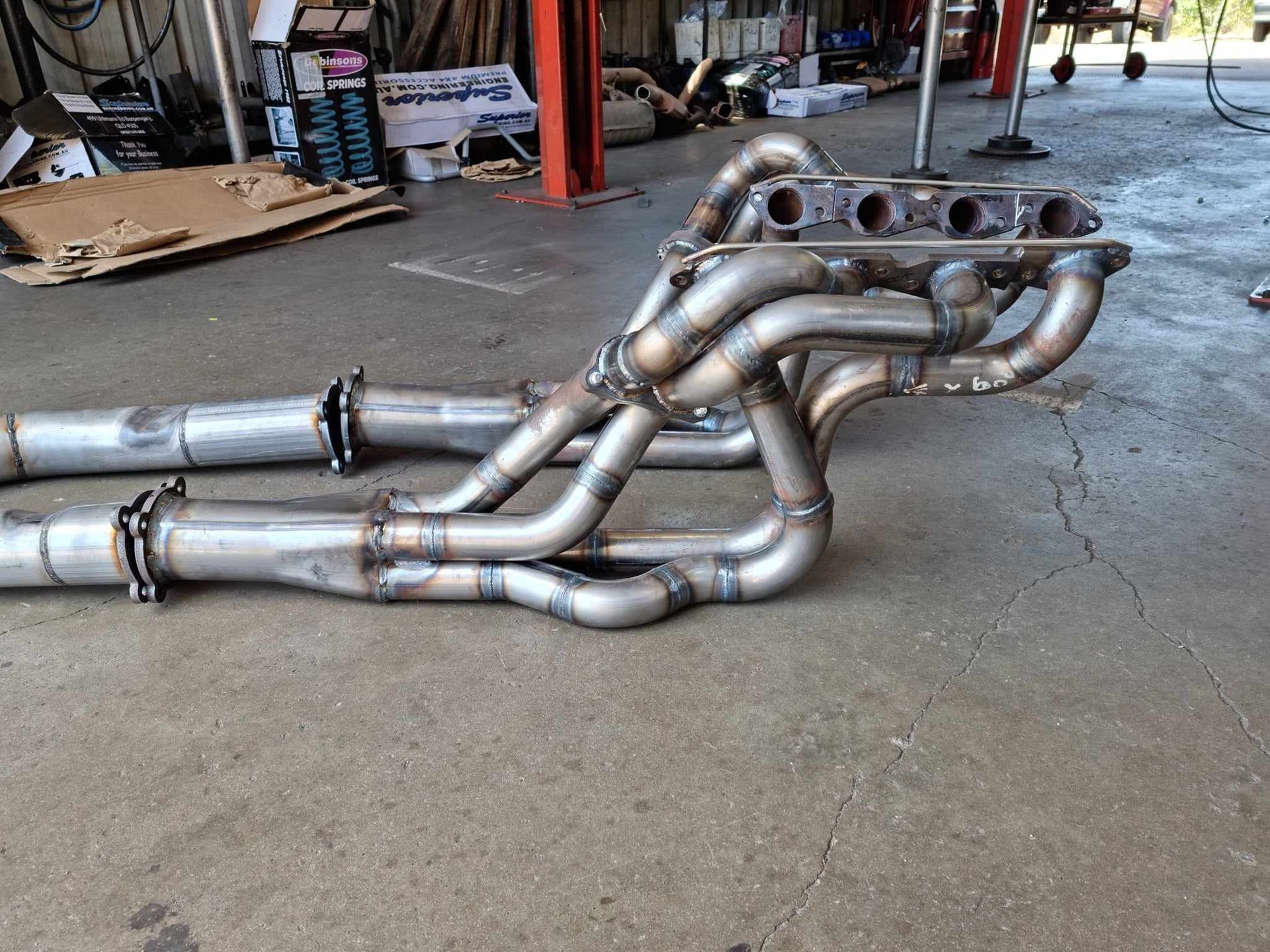 A Close up Of a Car Exhaust Pipe on A Lift — Rum City Exhaust Centre in Bundaberg Central, QLD