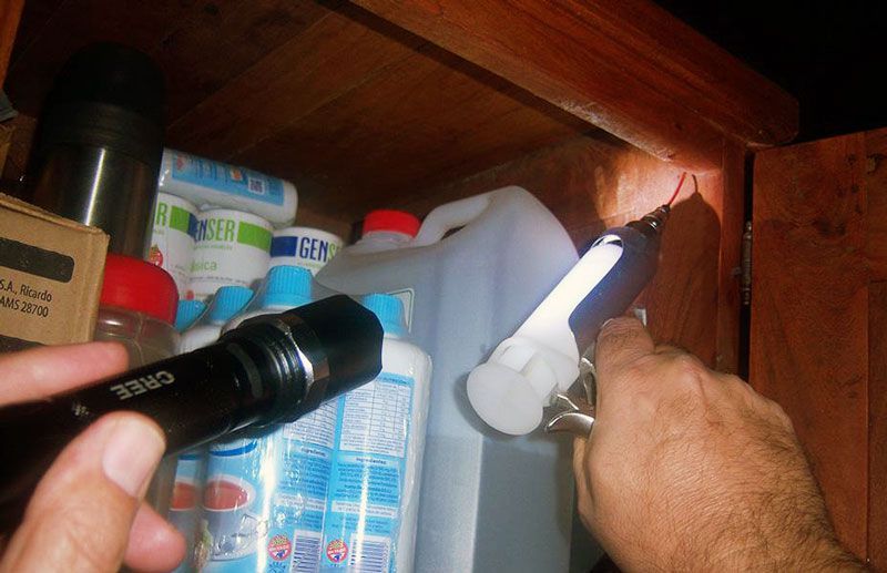 Manos sosteniendo linternas, inspeccionando el interior de un armario desordenado.