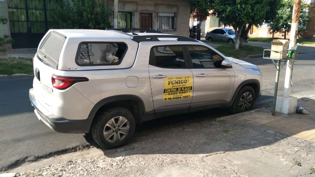 Camioneta blanca con capota blanca estacionada en una calle al lado de un buzón.