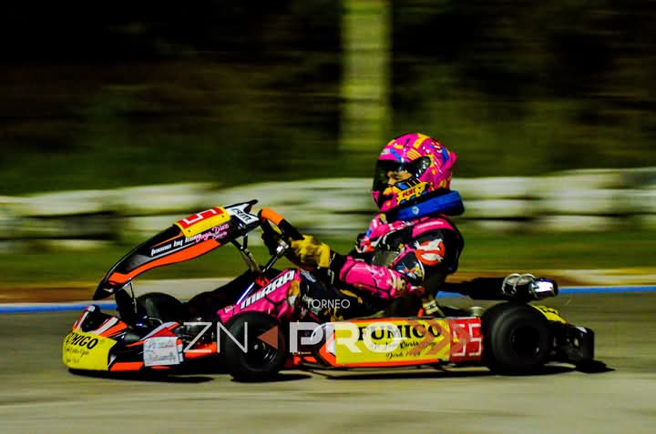 Corredor de karts en color rosa, negro y amarillo corriendo de noche.