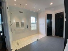 A bathroom with a walk in shower and black doors.