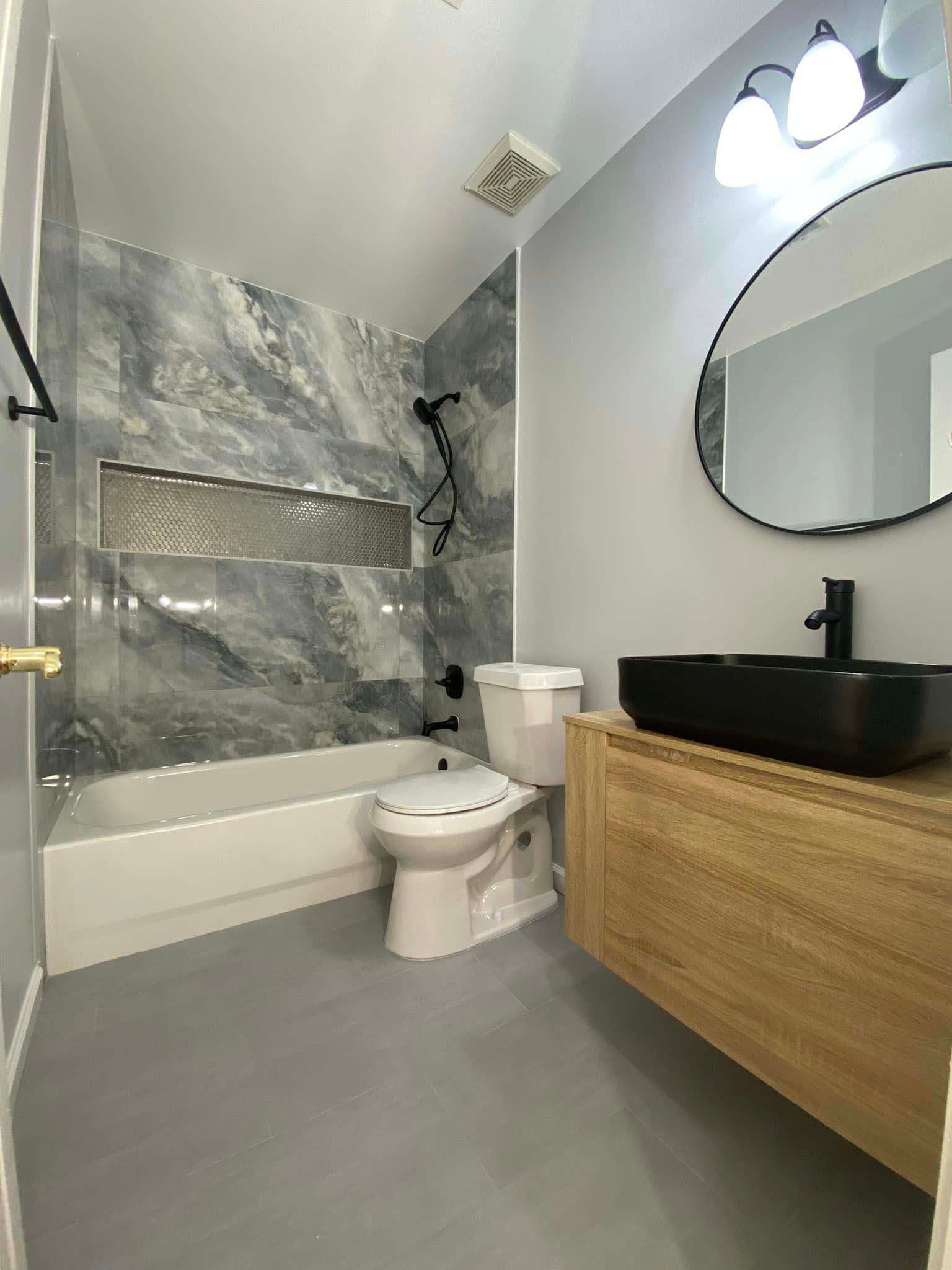 A bathroom with a toilet , sink , bathtub and mirror.