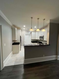 An empty kitchen with white cabinets and a black counter top.