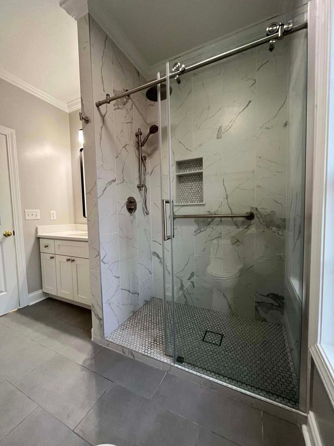 A bathroom with a walk in shower and a sink.