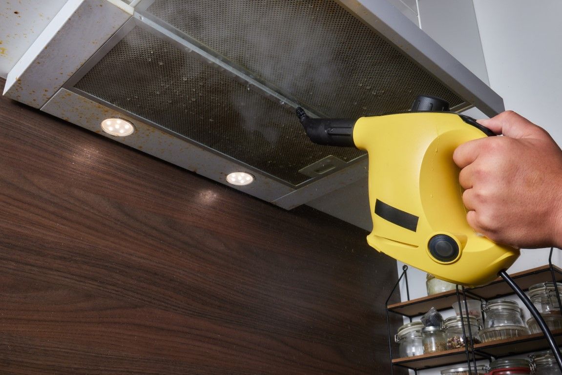 Worker pressure washing a commercial kitchen exhaust hood.