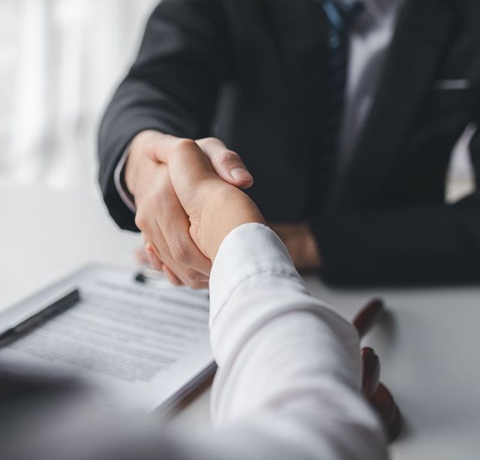 A man in a suit and tie is shaking hands with a woman in a white shirt.