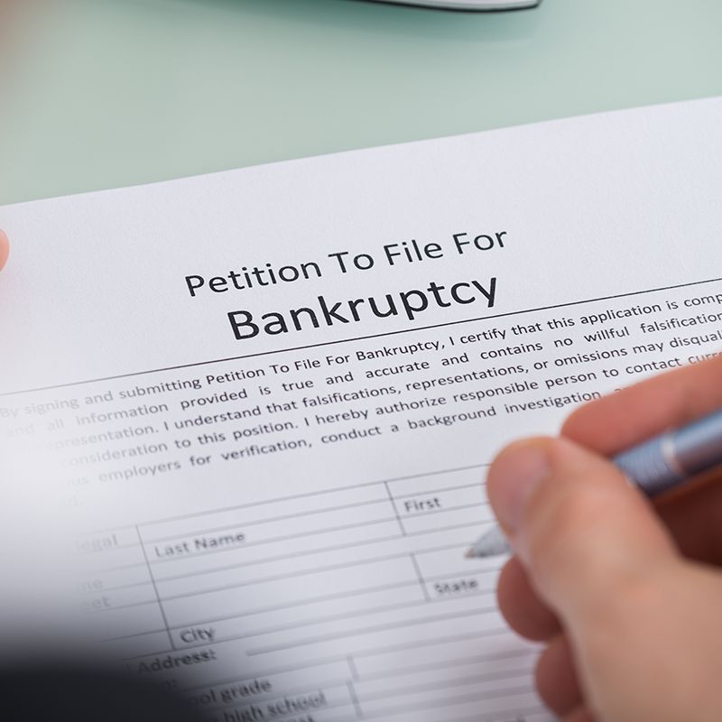 A person is filling out a petition to file for bankruptcy
