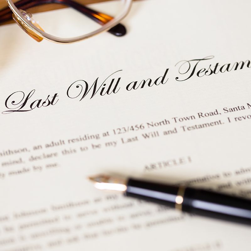 A pen sits on top of a last will and testament