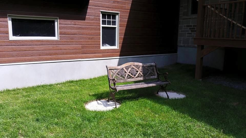 Un banc en bois est assis dans l'herbe devant une maison.