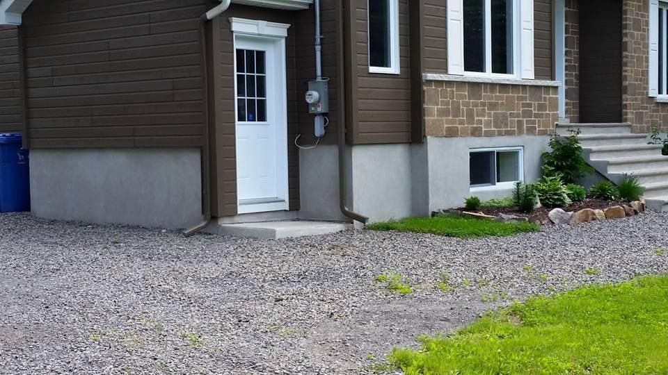 Une maison avec une allée de gravier devant elle