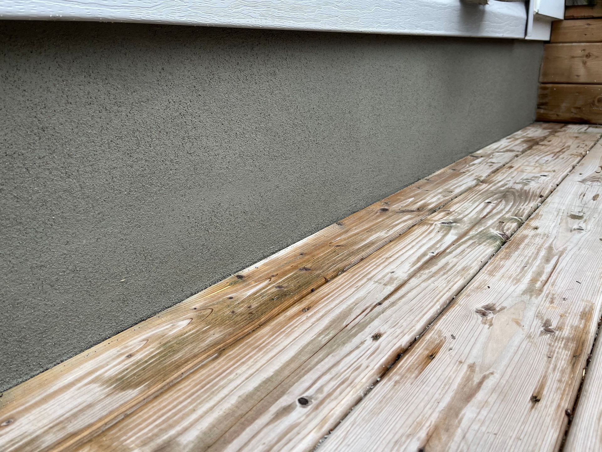 Une terrasse en bois avec un mur en béton en arrière-plan.
