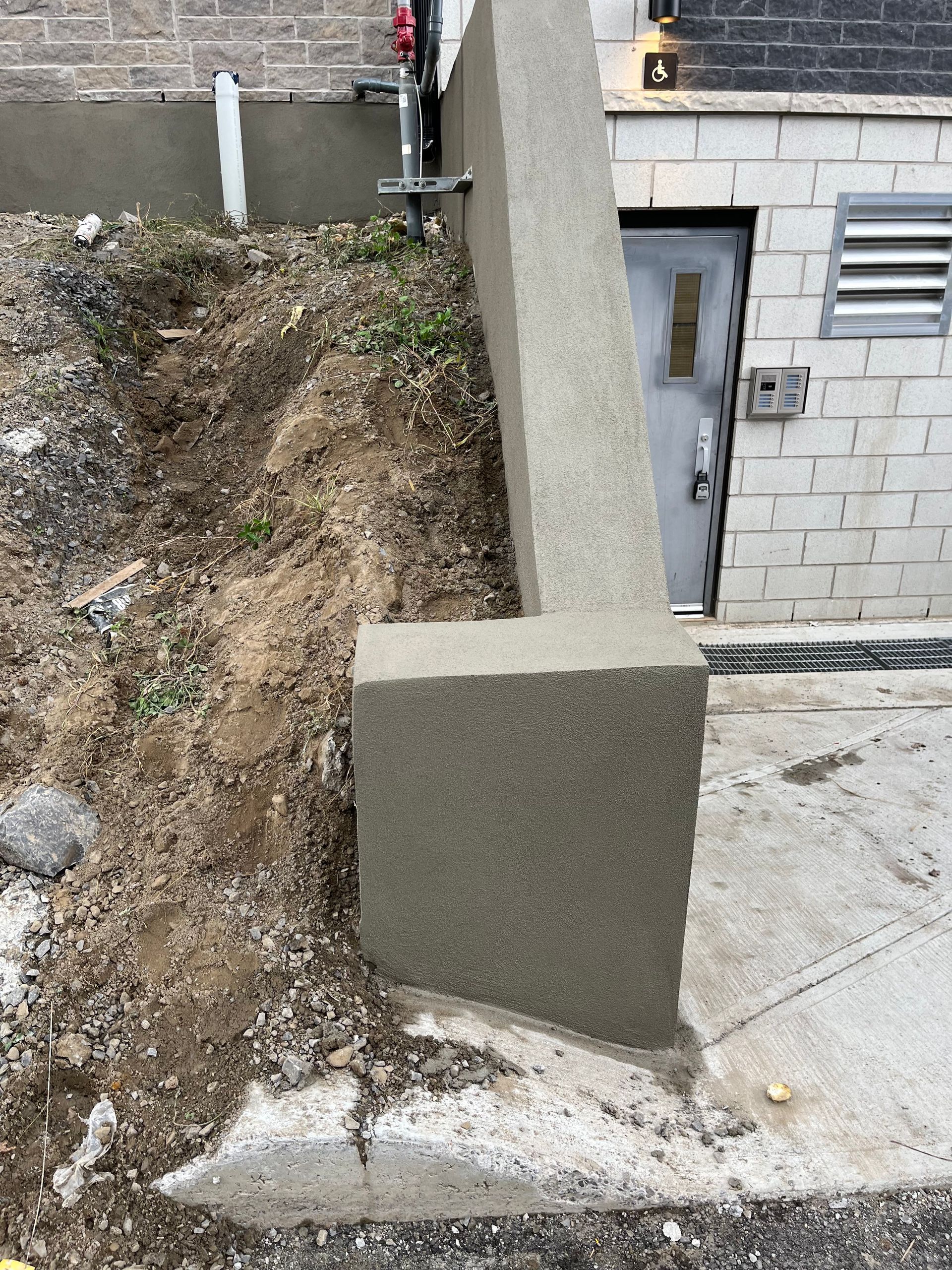 Un mur de béton est en construction devant un bâtiment en briques