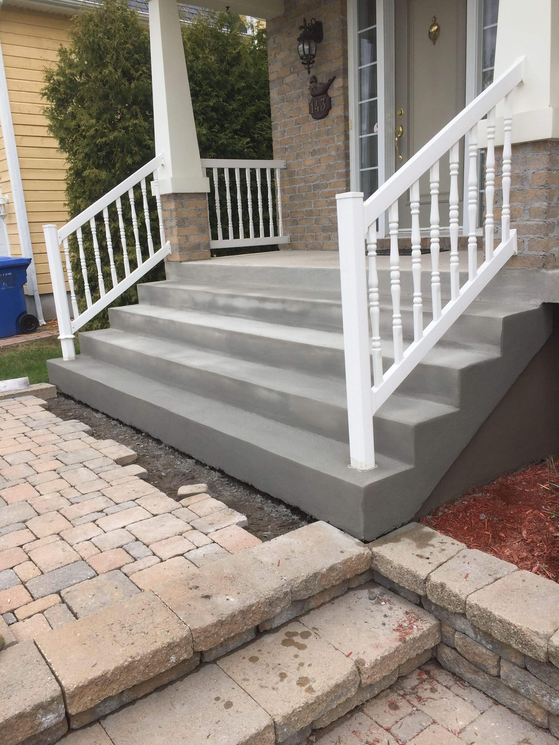 Un escalier en béton avec une rampe blanche