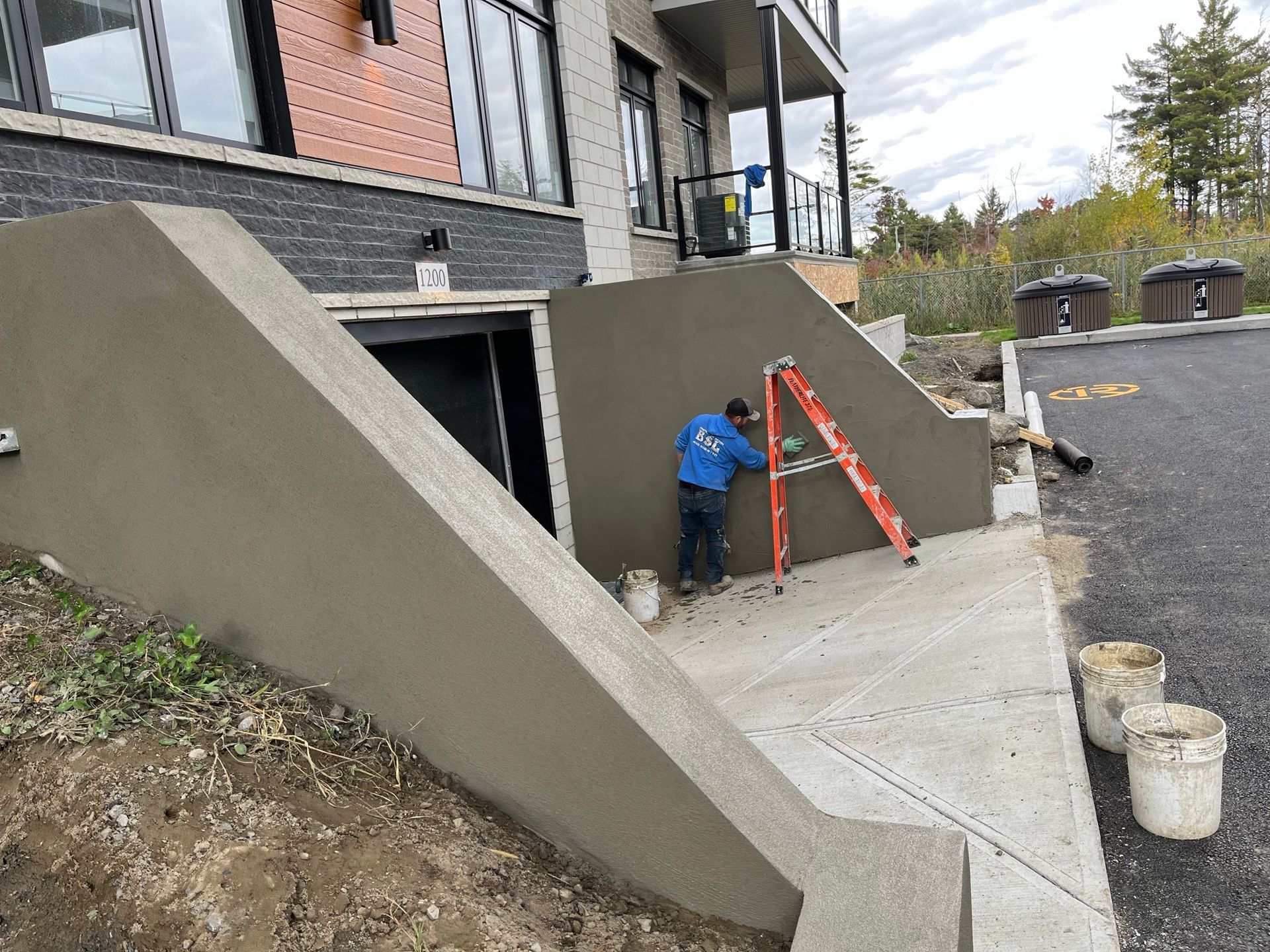 Un homme se tient devant un bâtiment en train de peindre un mur.