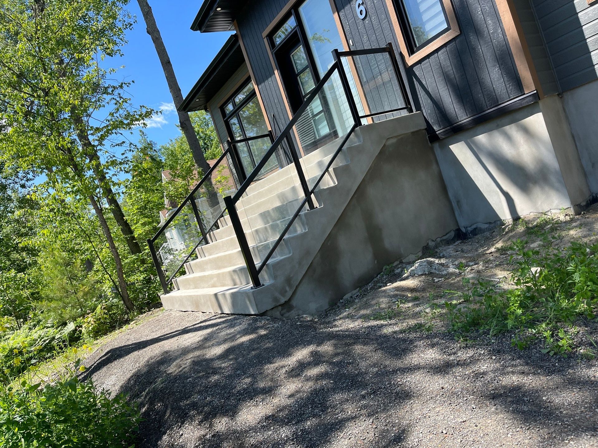Une maison avec des escaliers qui y mènent et une balustrade en verre.