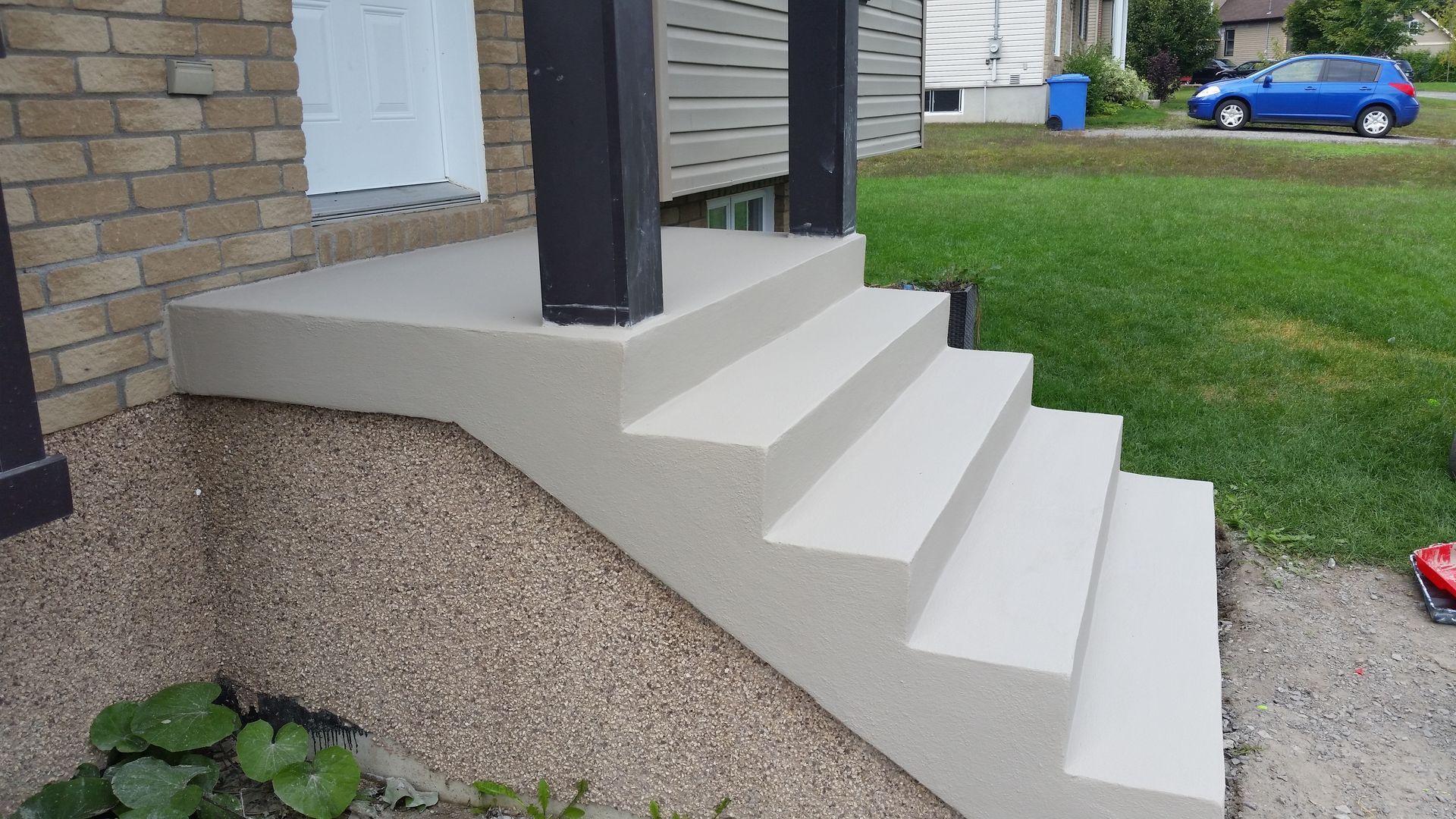 Un ensemble d'escaliers menant à un porche avec une voiture bleue garée en arrière-plan.