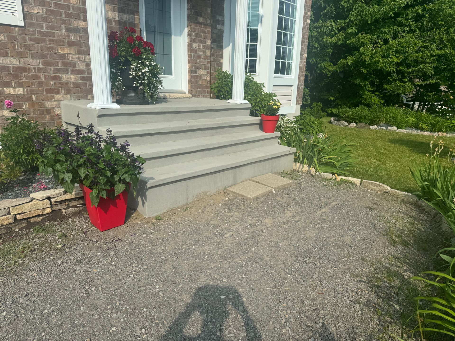 L'ombre d'une personne est projetée sur le gravier devant une maison