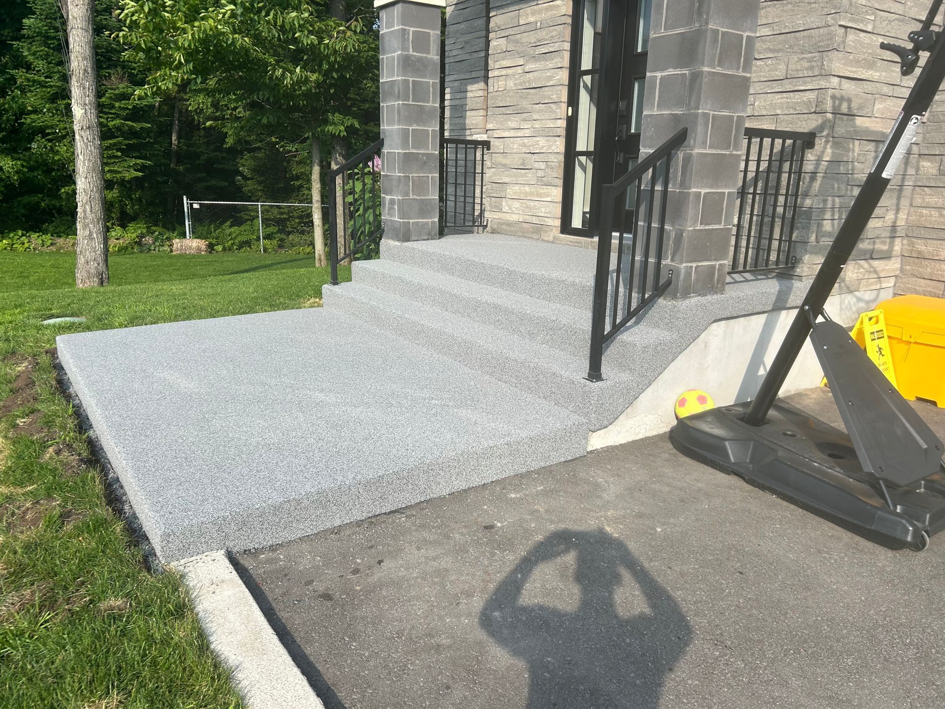 L'ombre d'une personne est projetée sur le trottoir devant une maison.