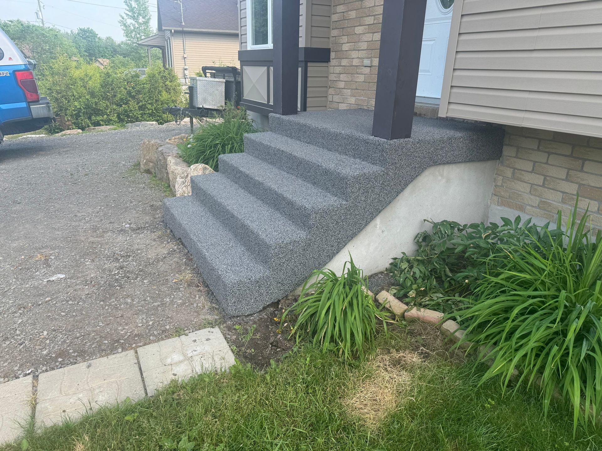 Une voiture est garée devant une maison avec des escaliers qui y mènent.
