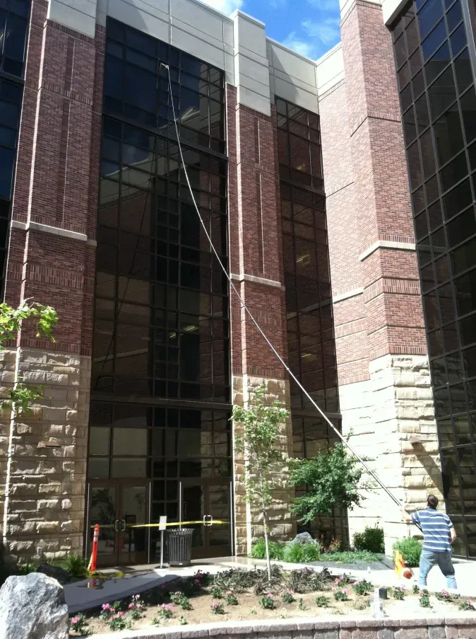 A man is cleaning the windows of a large brick building