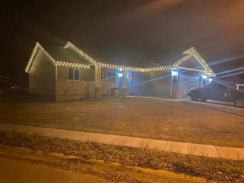A house with christmas lights on it is lit up at night.