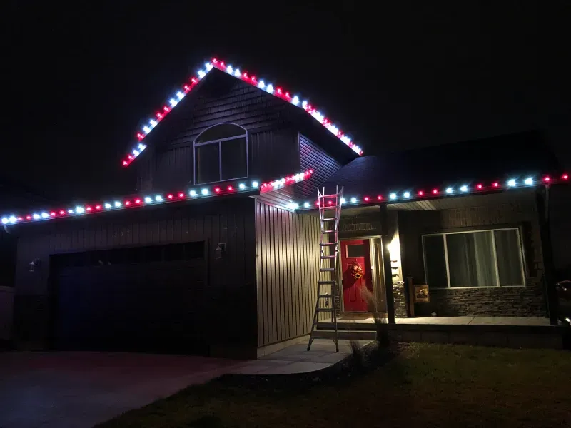 A house is decorated with red , white and blue christmas lights.