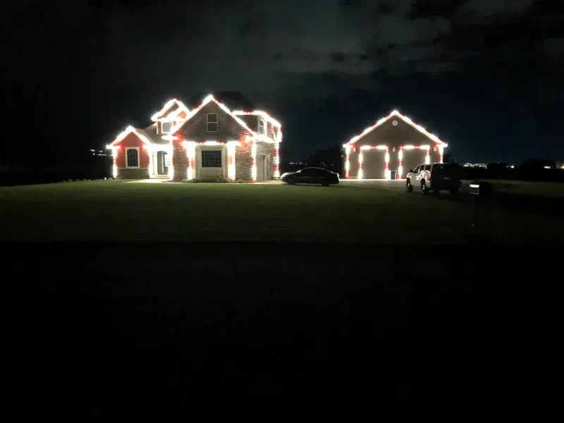 A house and a garage are lit up at night