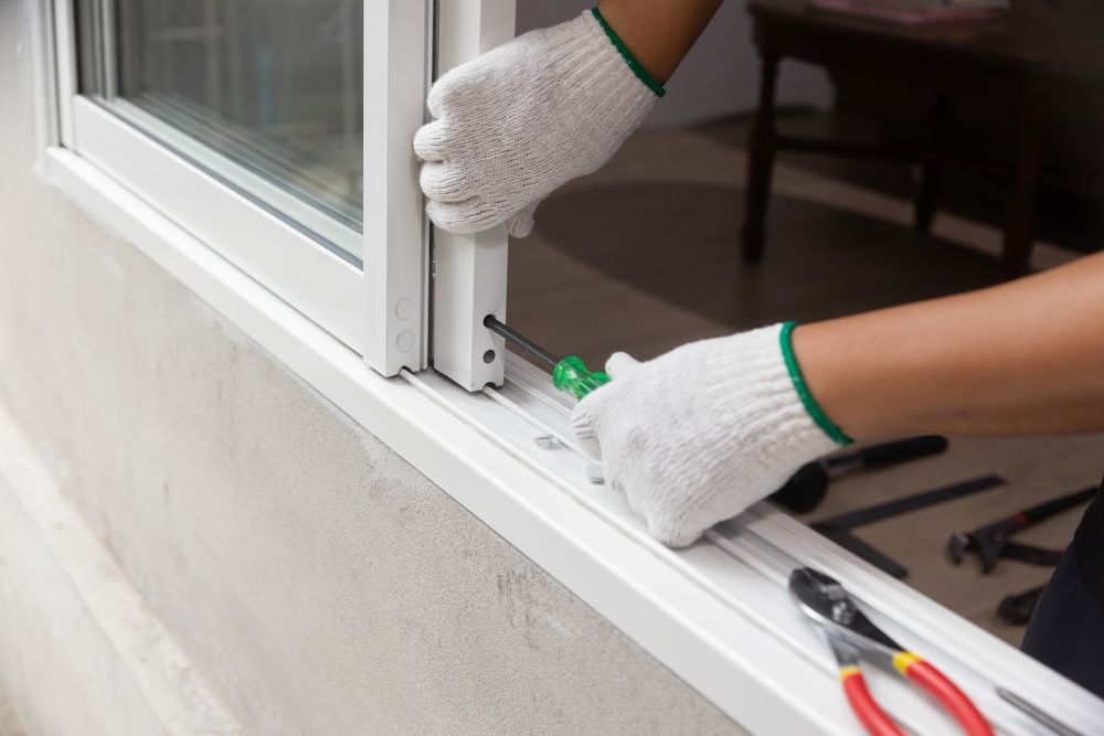 A person is installing a window with a screwdriver and pliers.