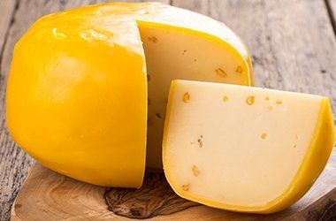 a yellow cheese is sitting on a wooden cutting board .