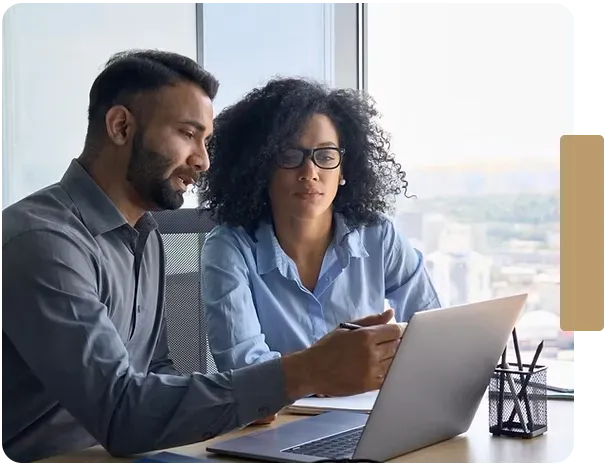 A man and a woman are looking at a laptop computer.