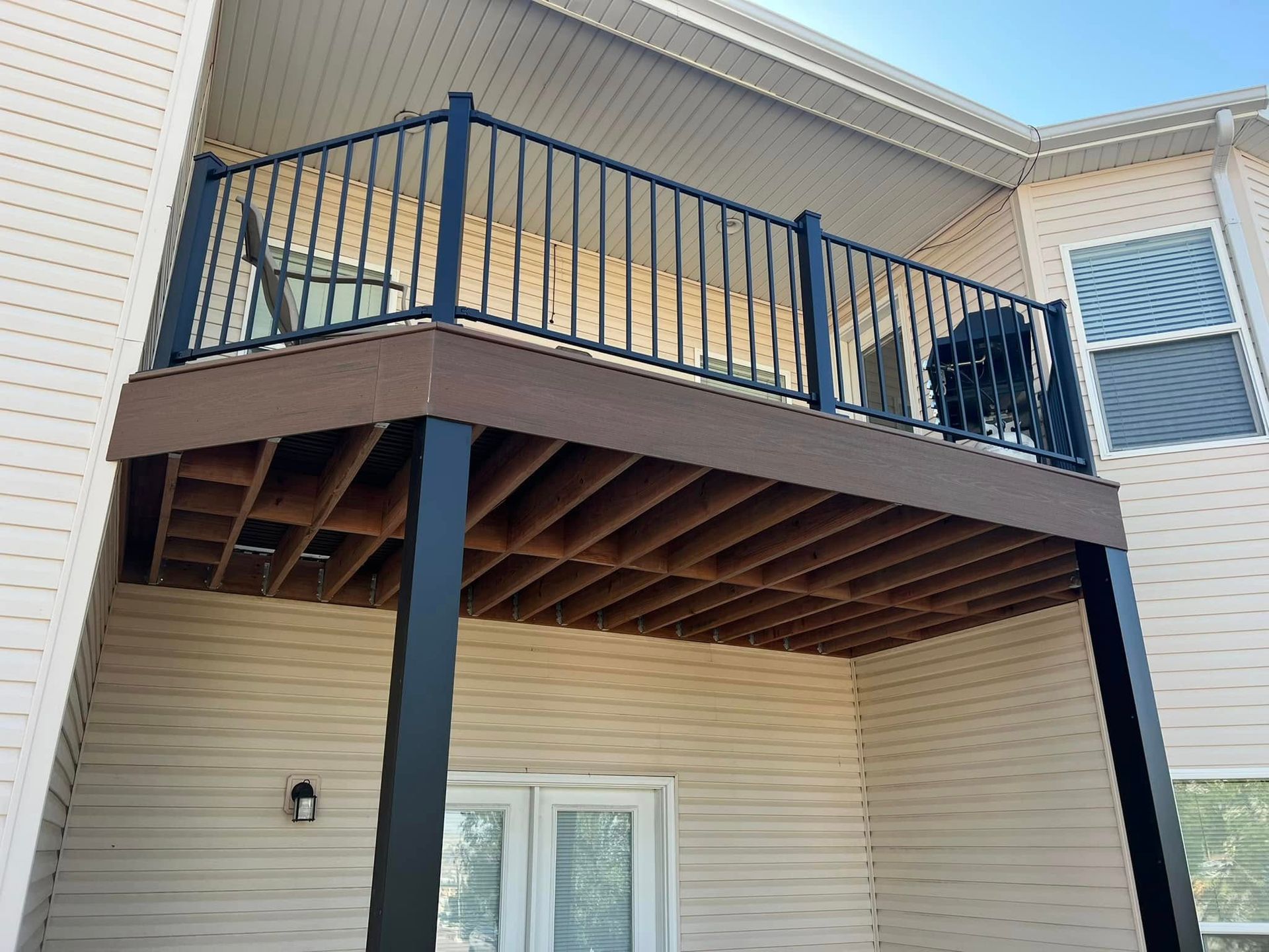 A balcony with a black railing is on the side of a house.