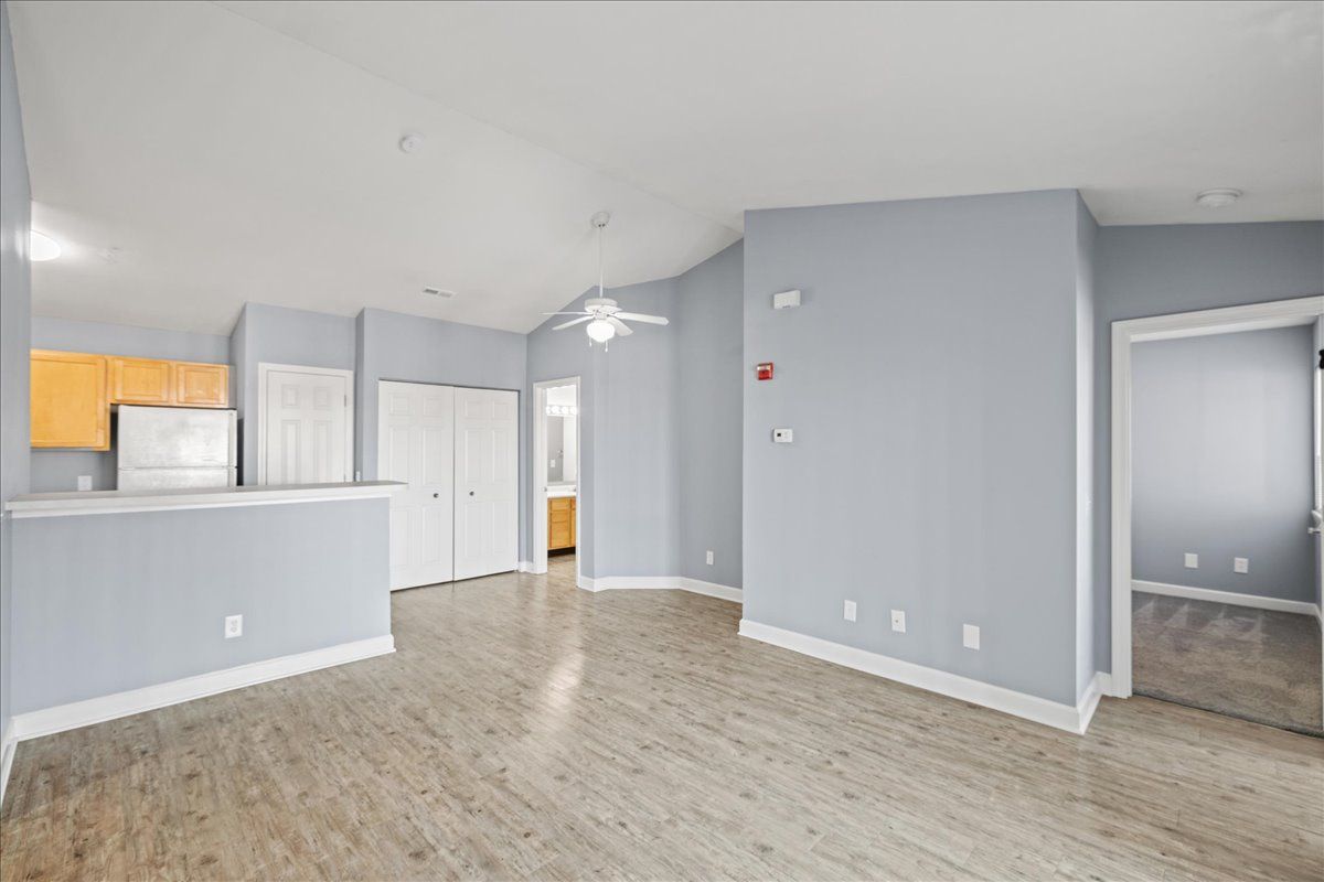 An empty living room with hardwood floors and a ceiling fan.