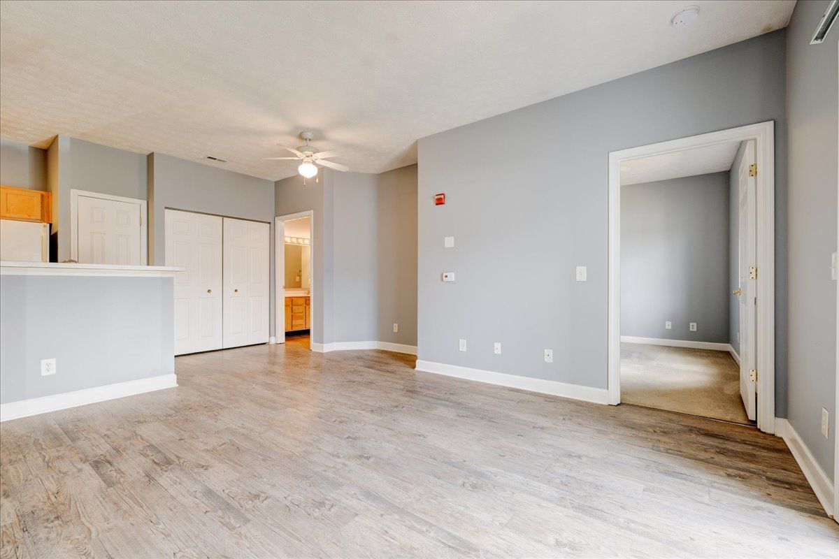 An empty living room with hardwood floors and a ceiling fan.