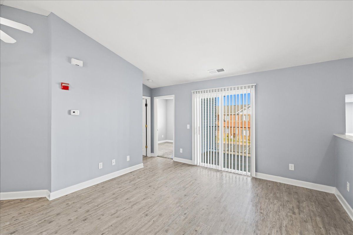 An empty living room with sliding glass doors and a ceiling fan.