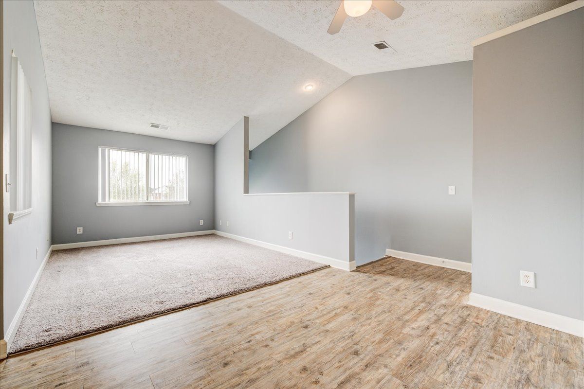 An empty living room with hardwood floors and a ceiling fan.