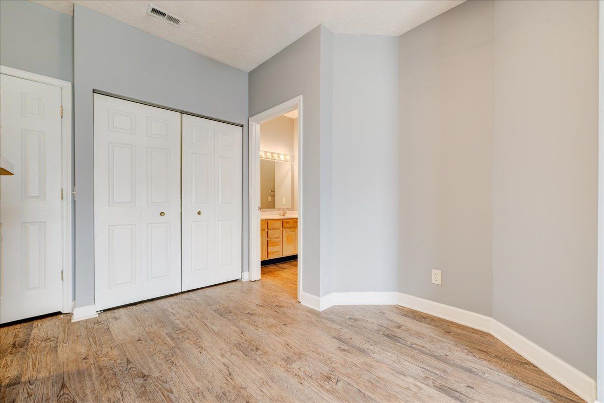 An empty bedroom with hardwood floors and a closet.