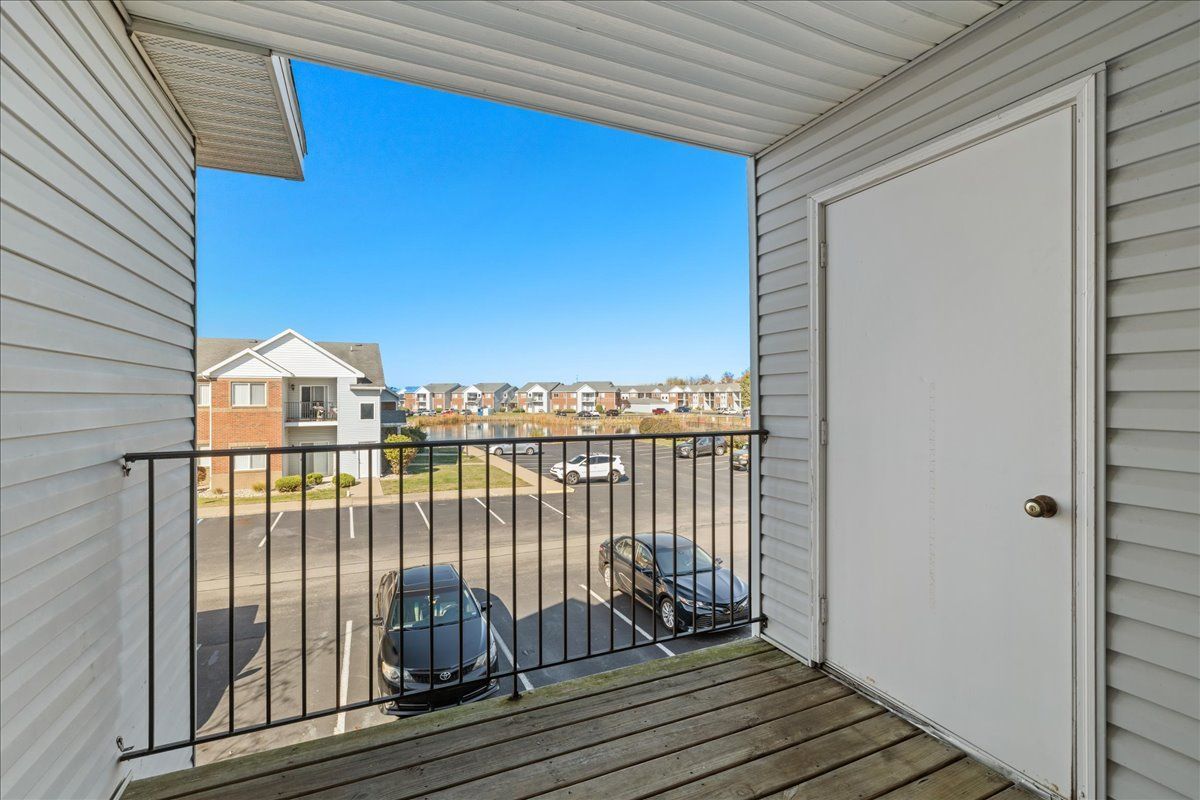 A balcony in a house with a view of a parking lot.