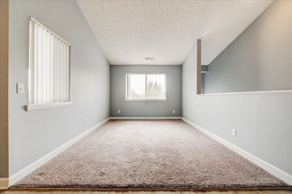 An empty living room with a window and carpet