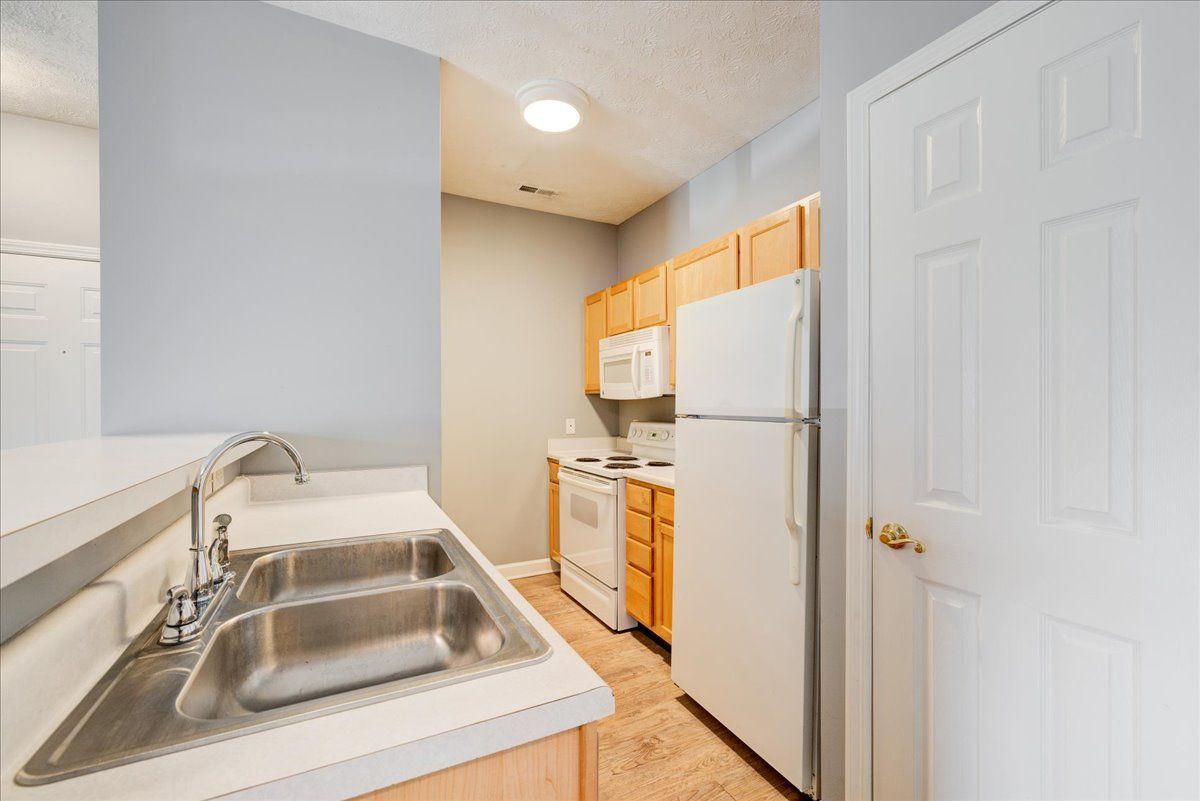 A kitchen with a sink , refrigerator , stove and microwave.