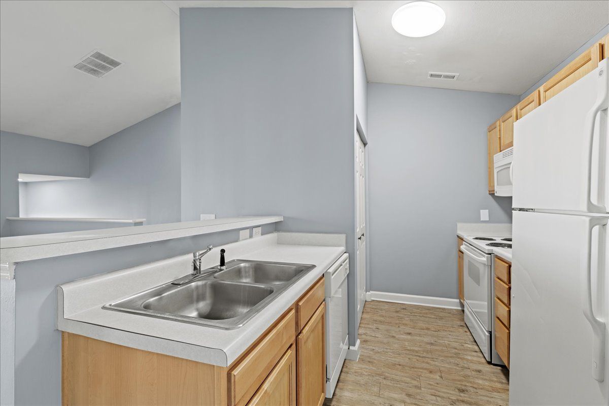 A kitchen with a sink , refrigerator , stove and microwave.