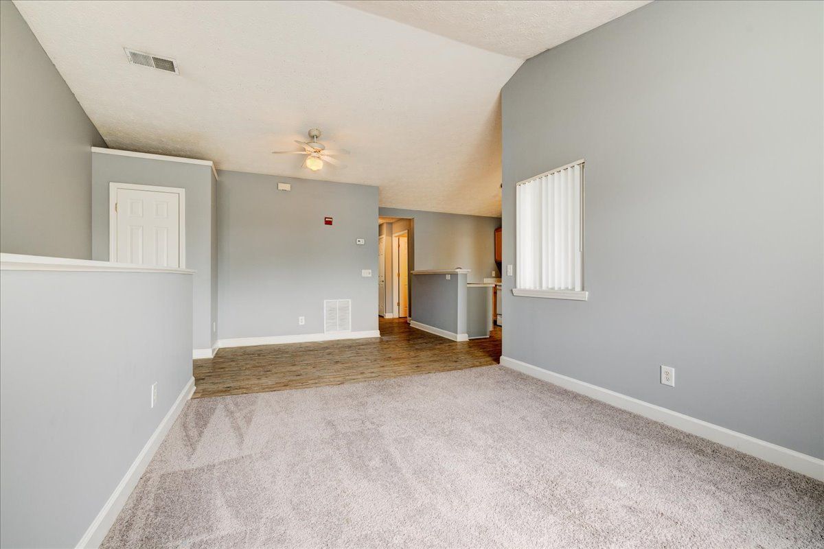 An empty living room with gray walls and a carpeted floor.
