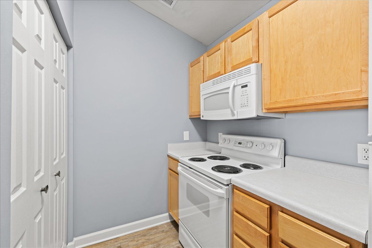 A kitchen with a stove , microwave , and cabinets.