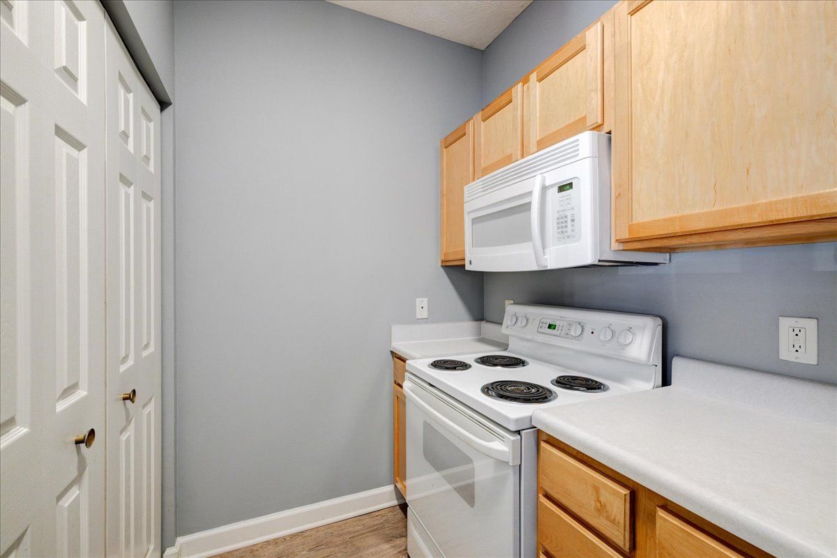 A kitchen with a stove , microwave , and cabinets.