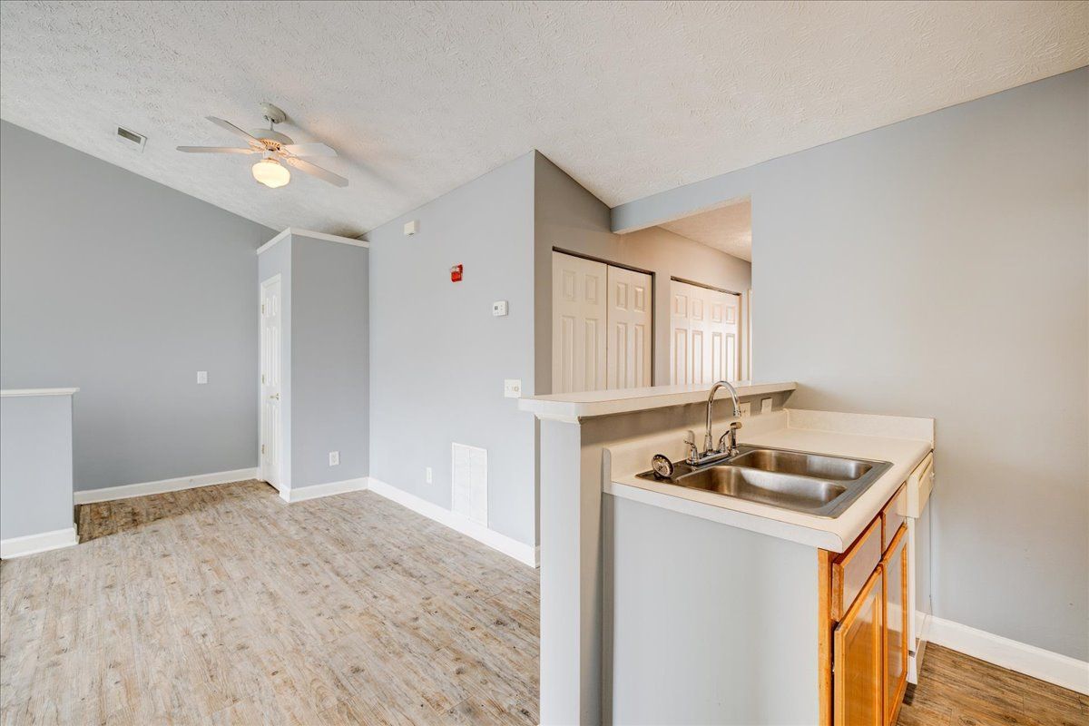 An empty kitchen with a sink and a ceiling fan.