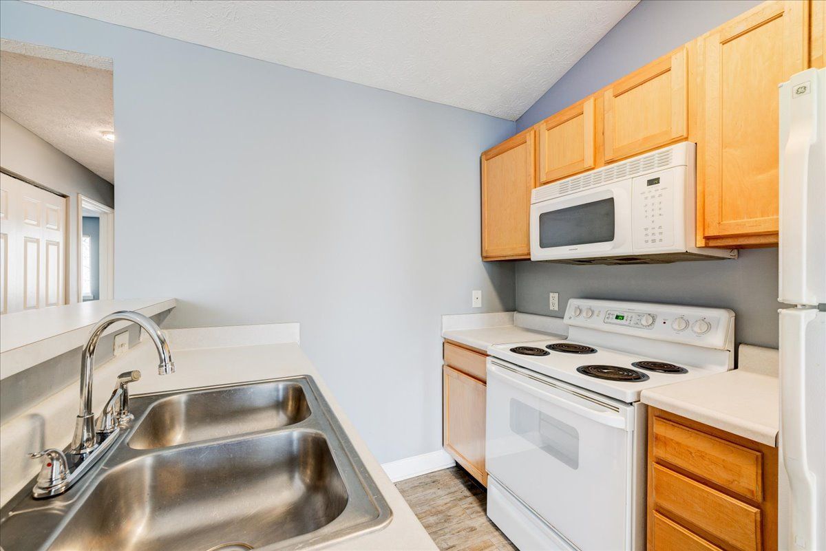 A kitchen with a sink , stove , microwave and refrigerator.
