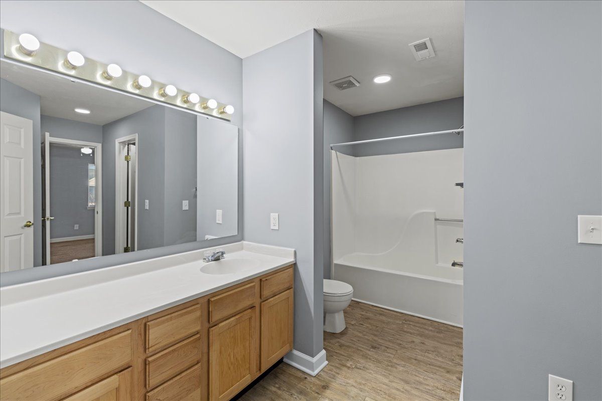 A bathroom with a sink , toilet , bathtub and mirror.