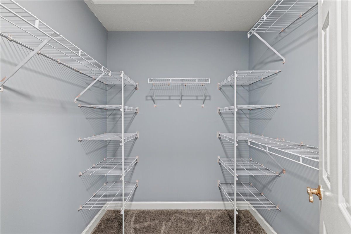 A walk in closet with lots of shelves and a door.